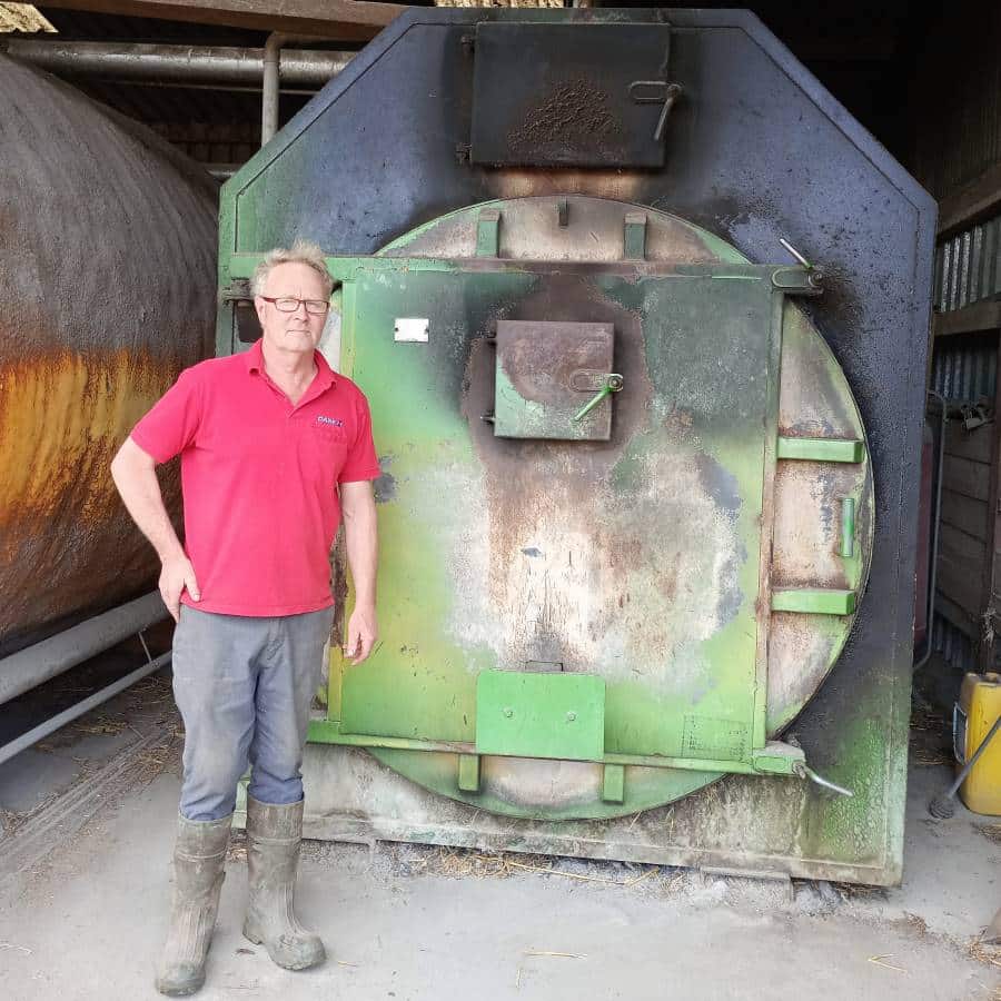 Mark Andrews stands next to his biomass boiler on Buryend Farm